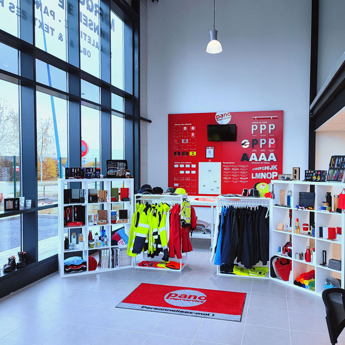 Showroom client dans une agence PANO avec mur de lettres découpées pour enseigne, textile professionnel pour marquage